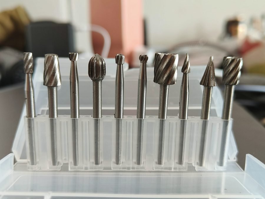 A row of carbide burrs in assorted shapes standing in a clear case