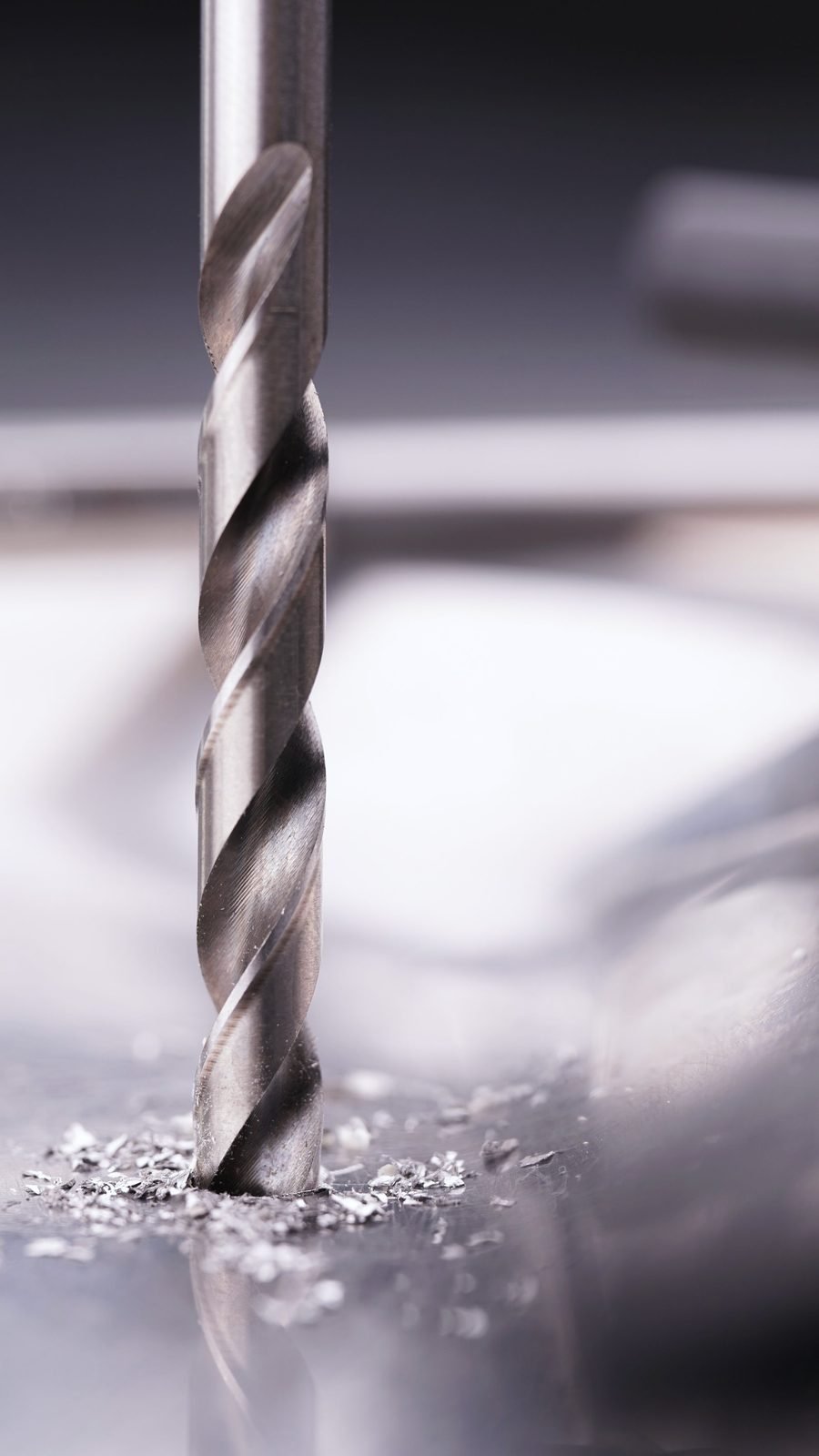 A twist drill starting a hole in steel with fine swarf around the point