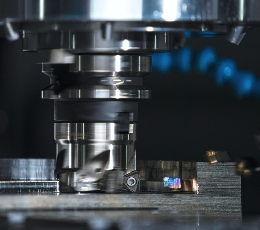 A face mill with indexable inserts skimming the top of a steel block