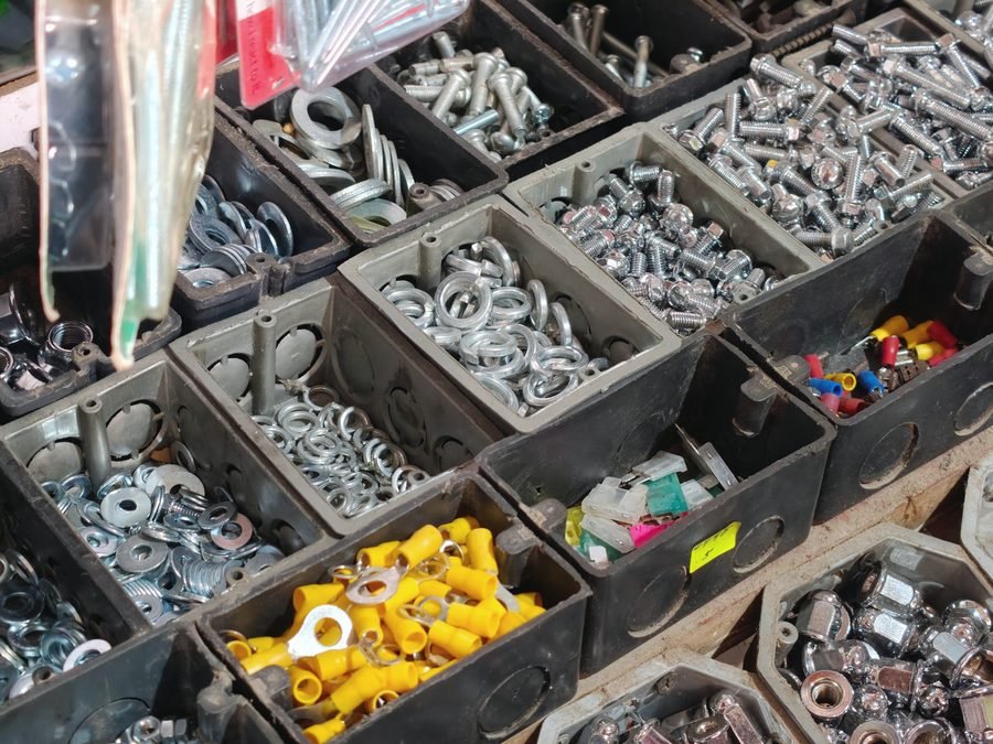 Open black bins of washers, nuts, bolts and yellow crimp terminals